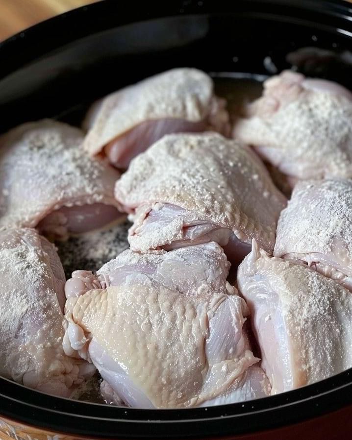 Coat chicken in flour and toss in slow cooker