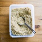 "Homemade sourdough breadcrumbs in a rustic bowl with slices of sourdough bread on a wooden board."